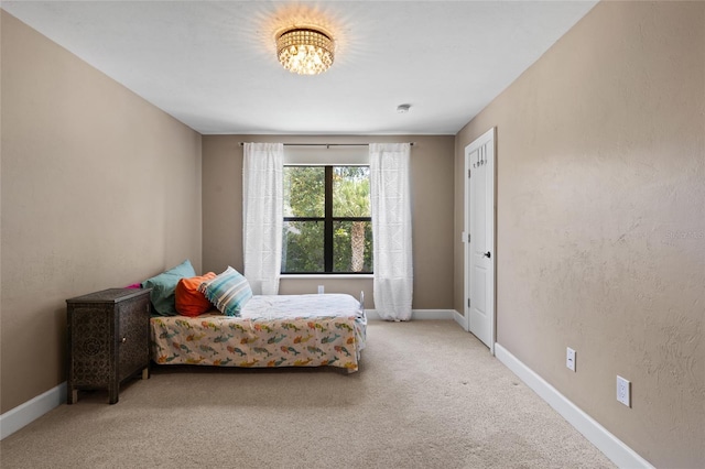 carpeted bedroom featuring baseboards and a chandelier