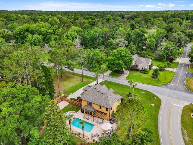 drone / aerial view of a heavily wooded area and a pool area