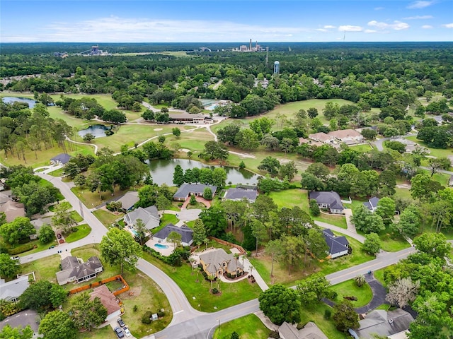 aerial perspective of suburban area with a nearby body of water and a heavily wooded area