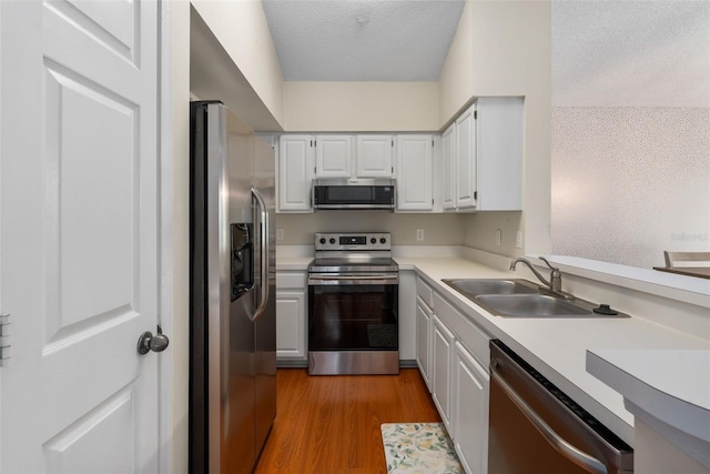 10000 SW 52nd Ave Unit J50, Gainesville, FL 32608 - kitchen featuring appliances with stainless steel finishes, a sink, light countertops, light wood-style floors, and white cabinetry