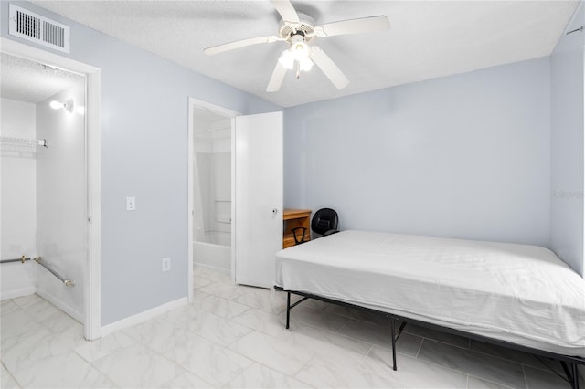 bedroom with light marble finish floors, a textured ceiling, a ceiling fan, ensuite bath, and baseboards
