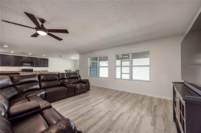 living area with a textured ceiling, ceiling fan, light wood-style flooring, baseboards, and recessed lighting