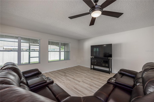 living room featuring a textured ceiling, a ceiling fan, light wood finished floors, and baseboards