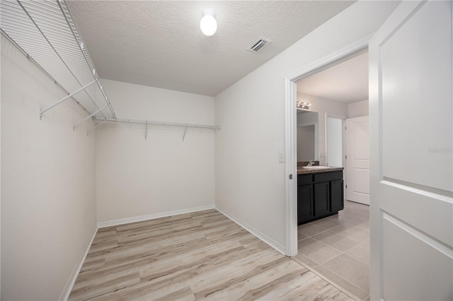 spacious closet featuring a sink and light wood-style floors