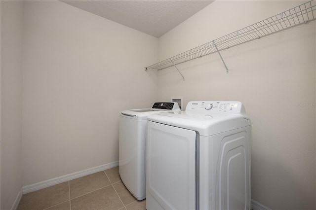 laundry room with washer and dryer, baseboards, and light tile patterned floors