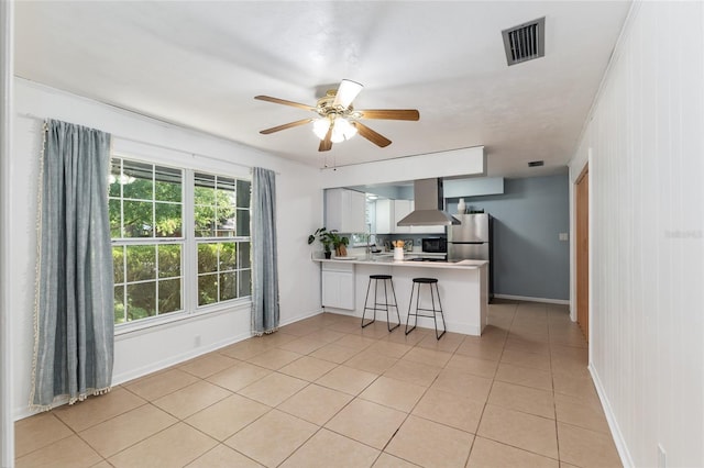 5610 NW 29th Ter, Gainesville, FL 32653 - kitchen featuring wall chimney range hood, freestanding refrigerator, a peninsula, light countertops, and ceiling fan