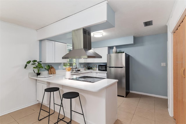 5610 NW 29th Ter, Gainesville, FL 32653 - kitchen featuring black appliances, island range hood, a peninsula, light tile patterned flooring, and a breakfast bar area