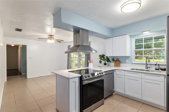 5610 NW 29th Ter, Gainesville, FL 32653 - kitchen with stainless steel appliances, wall chimney range hood, a peninsula, light countertops, and plenty of natural light