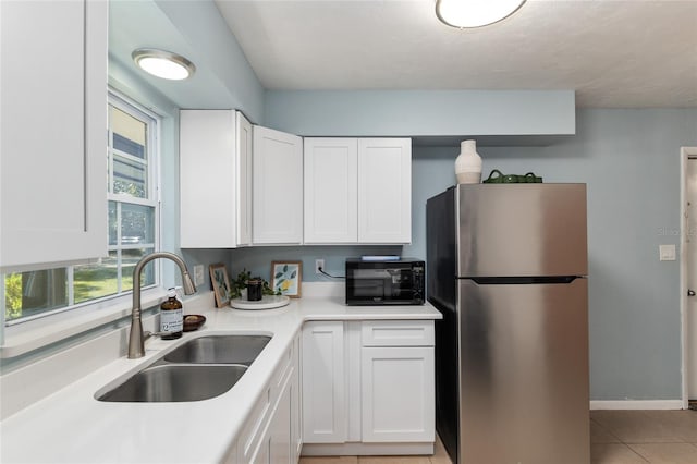 5610 NW 29th Ter, Gainesville, FL 32653 - kitchen with freestanding refrigerator, black microwave, white cabinets, light countertops, and light tile patterned floors