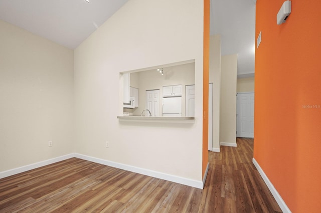 9119 SW 52nd Ave Unit C301, Gainesville, FL 32608 - unfurnished living room featuring wood finished floors, baseboards, and high vaulted ceiling