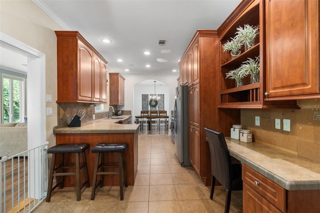 14204 SW 70th St, Archer, FL 32618 - kitchen with freestanding refrigerator, a sink, tasteful backsplash, a kitchen breakfast bar, and arched walkways