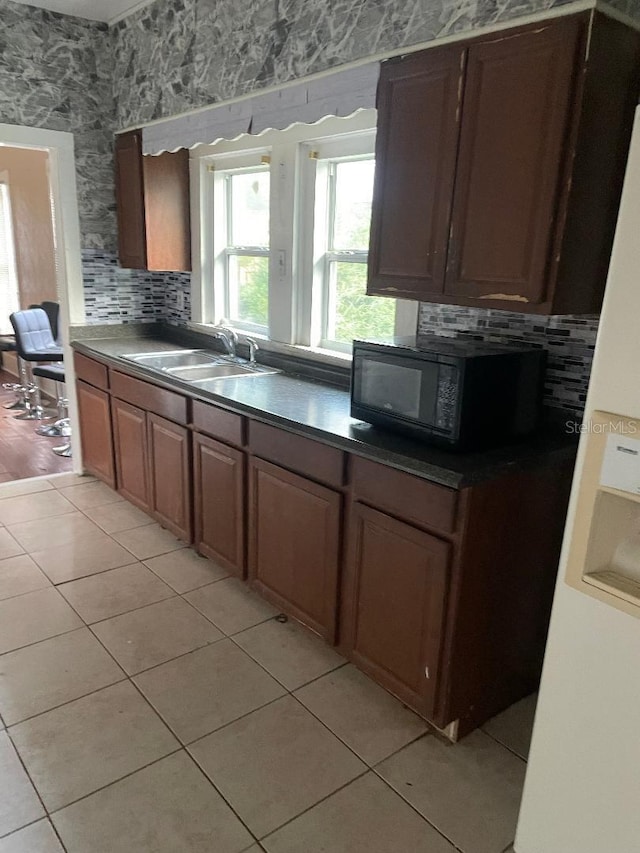 31 NW 4th St, Williston, FL 32696 - kitchen featuring black microwave, wallpapered walls, light tile patterned flooring, decorative backsplash, and a sink