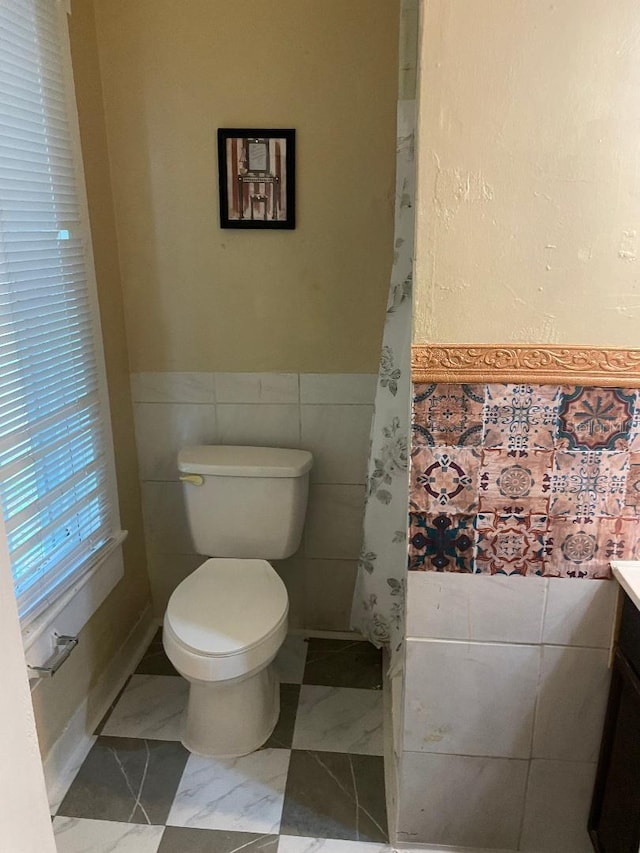 31 NW 4th St, Williston, FL 32696 - bathroom with tile walls, toilet, vanity, and a wainscoted wall