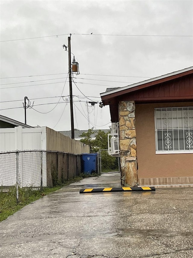 6019 W Fern St, Tampa, FL 33634 - view of property exterior with stone siding, fence, cooling unit, stucco siding, and a gate
