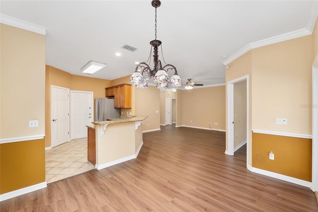 3664 NW 55th Ln, Gainesville, FL 32653 - kitchen with freestanding refrigerator, a ceiling fan, baseboards, light wood-type flooring, and a kitchen bar