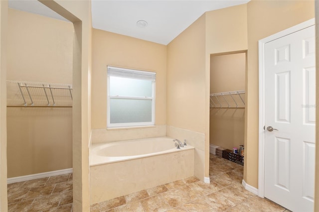 3664 NW 55th Ln, Gainesville, FL 32653 - bathroom with a bath, a walk in closet, and baseboards