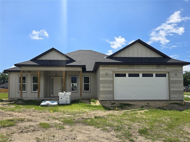 view of front of home featuring board and batten siding, roof with shingles, an attached garage, driveway, and covered porch