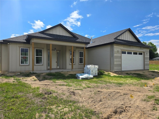 view of front of house with board and batten siding, a garage, roof with shingles, and driveway