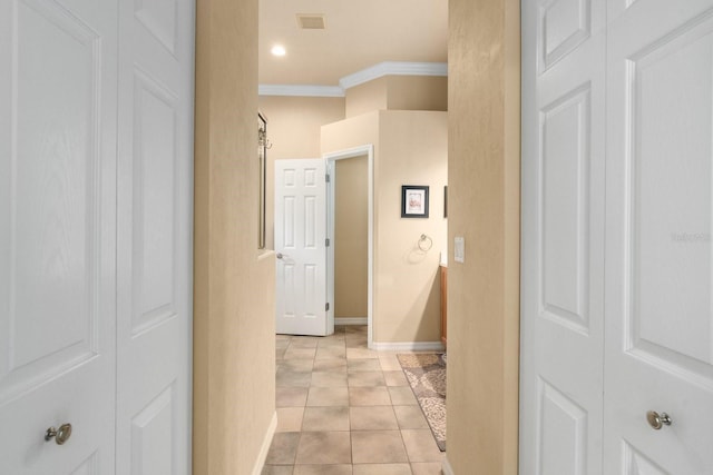 hall featuring crown molding, baseboards, and light tile patterned floors