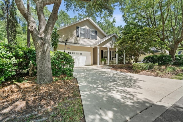 traditional-style house featuring driveway, covered porch, and a garage