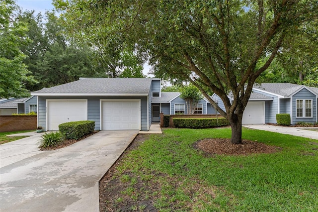 view of front of home featuring concrete driveway, a front yard, a garage, and a shingled roof