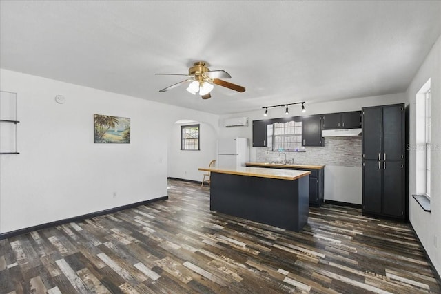 203 1st Ave SE, Steinhatchee, FL 32359 - kitchen featuring freestanding refrigerator, a wall unit AC, under cabinet range hood, a sink, and arched walkways