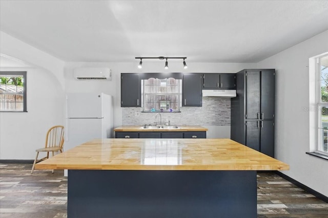 203 1st Ave SE, Steinhatchee, FL 32359 - kitchen featuring a sink, a wall mounted air conditioner, freestanding refrigerator, under cabinet range hood, and butcher block counters