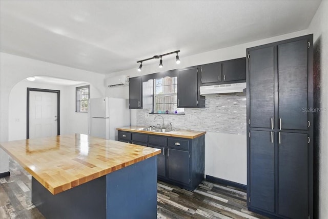 203 1st Ave SE, Steinhatchee, FL 32359 - kitchen featuring freestanding refrigerator, under cabinet range hood, arched walkways, a sink, and dark wood-style flooring