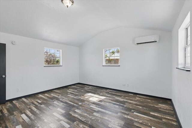 203 1st Ave SE, Steinhatchee, FL 32359 - unfurnished room featuring a wall unit AC, vaulted ceiling, wood finished floors, and baseboards