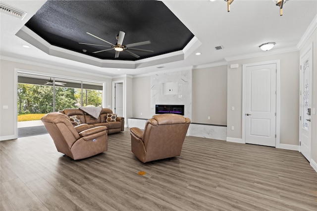 17781 SW 72nd Street Rd, Dunnellon, FL 34432 - living room featuring a raised ceiling, ceiling fan, ornamental molding, light wood-style floors, and a fireplace