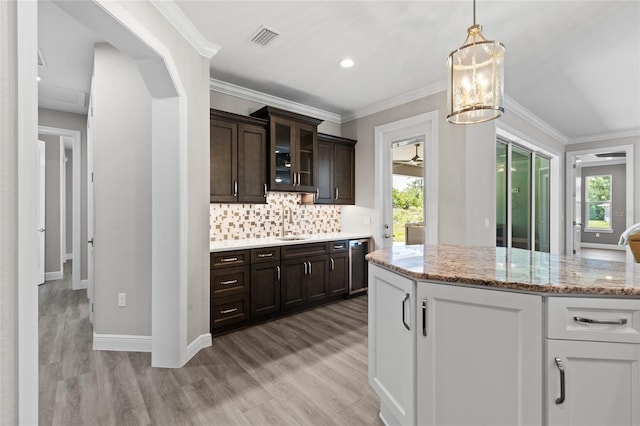 17781 SW 72nd Street Rd, Dunnellon, FL 34432 - kitchen with dark brown cabinetry, light wood-style floors, tasteful backsplash, glass insert cabinets, and ornamental molding