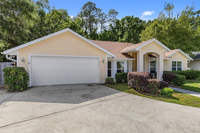 ranch-style home with driveway, roof with shingles, and an attached garage
