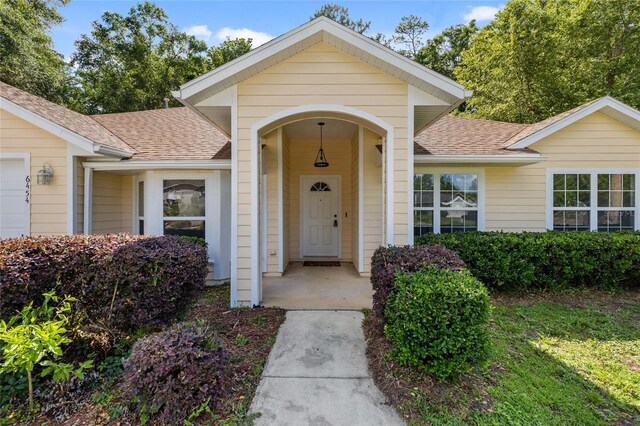 doorway to property with roof with shingles