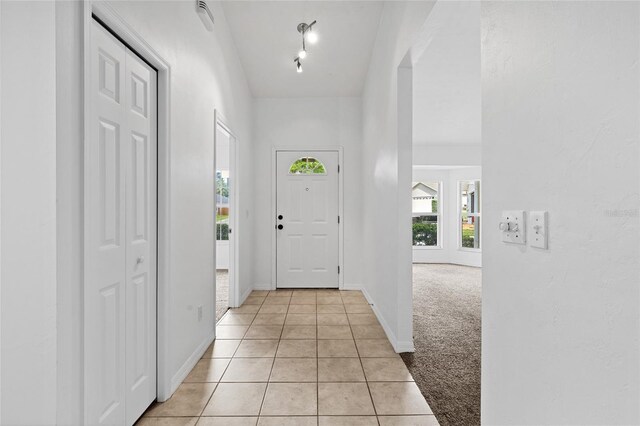 entrance foyer with light tile patterned floors, baseboards, and light colored carpet