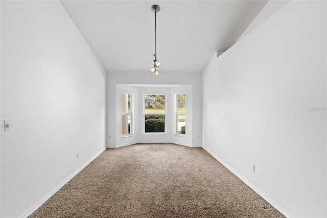 carpeted empty room featuring baseboards and vaulted ceiling