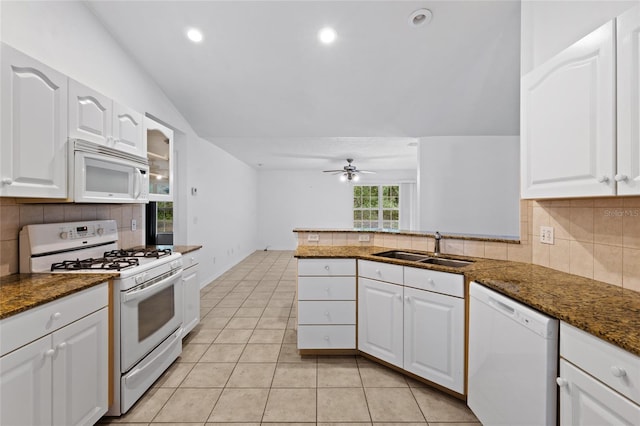 kitchen with white appliances, a sink, lofted ceiling, dark stone countertops, and white cabinetry