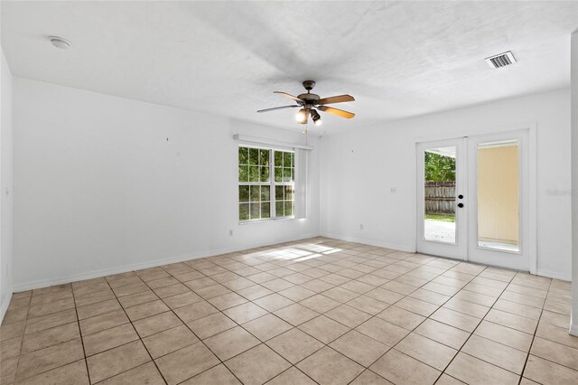 spare room with healthy amount of natural light, ceiling fan, light tile patterned flooring, and baseboards