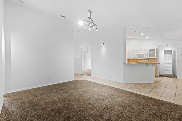 unfurnished living room featuring light tile patterned floors, light carpet, lofted ceiling, baseboards, and recessed lighting