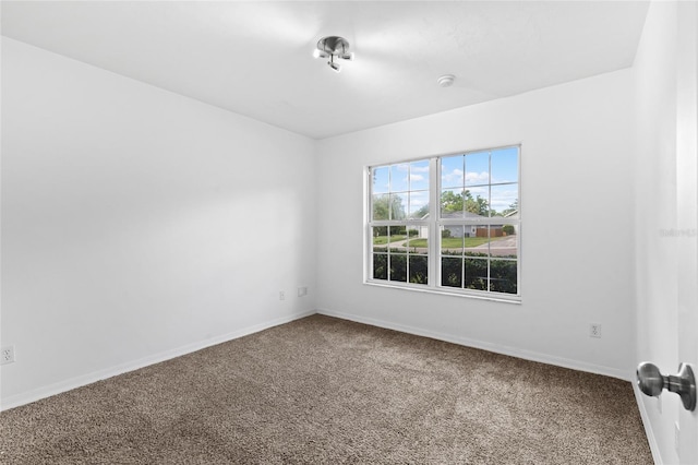 empty room featuring carpet, baseboards, and a smoke detector