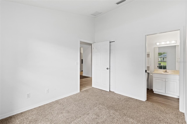 unfurnished bedroom featuring carpet floors, baseboards, a sink, and ensuite bathroom