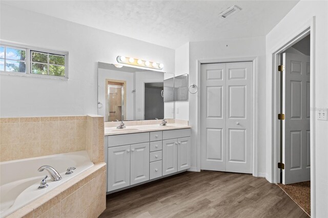 full bath featuring a garden tub, double vanity, a closet, an enclosed shower, and wood finished floors