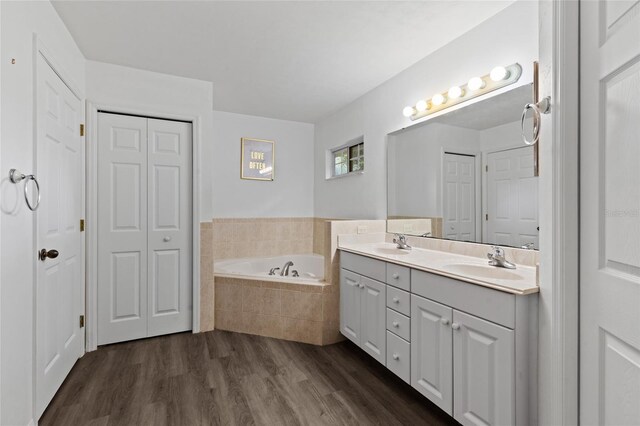 bathroom featuring a closet, a garden tub, wood finished floors, and double vanity