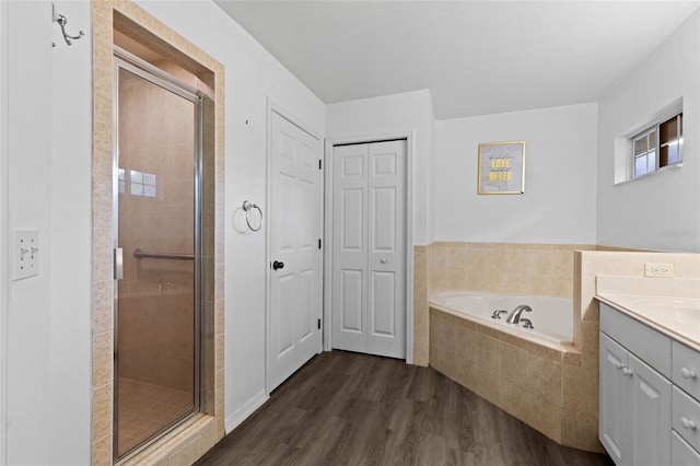 full bath featuring a stall shower, vanity, a garden tub, and wood finished floors