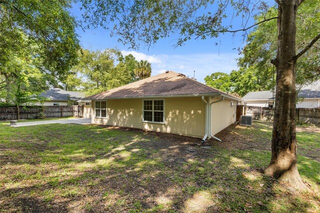 rear view of property with central AC unit, stucco siding, a patio, and a shingled roof