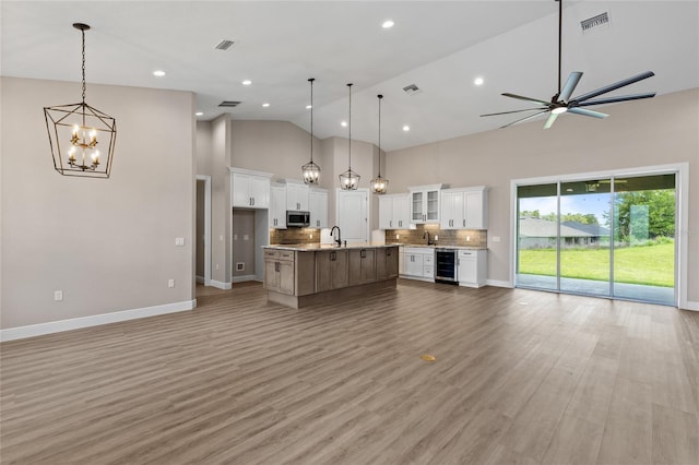 17887 SW 72nd Street Rd, Dunnellon, FL 34432 - kitchen with stainless steel microwave, beverage cooler, open floor plan, high vaulted ceiling, and a chandelier
