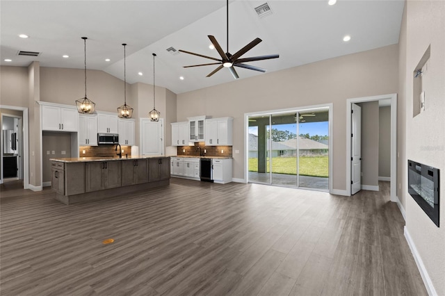 17887 SW 72nd Street Rd, Dunnellon, FL 34432 - kitchen with stainless steel microwave, open floor plan, high vaulted ceiling, white cabinets, and tasteful backsplash