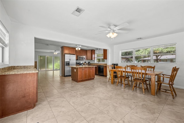 4023 SW 19th St, Gainesville, FL 32608 - kitchen with appliances with stainless steel finishes, a ceiling fan, a kitchen island, light countertops, and brown cabinetry
