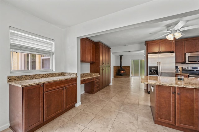 4023 SW 19th St, Gainesville, FL 32608 - kitchen featuring appliances with stainless steel finishes, a wood stove, healthy amount of natural light, and light stone countertops