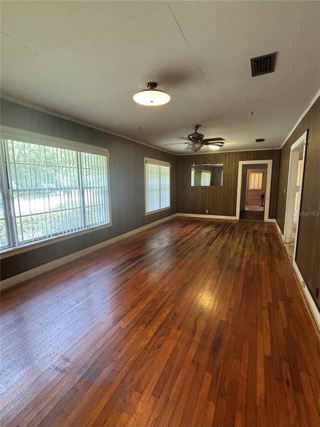 empty room featuring dark wood finished floors, ornamental molding, a ceiling fan, and baseboards