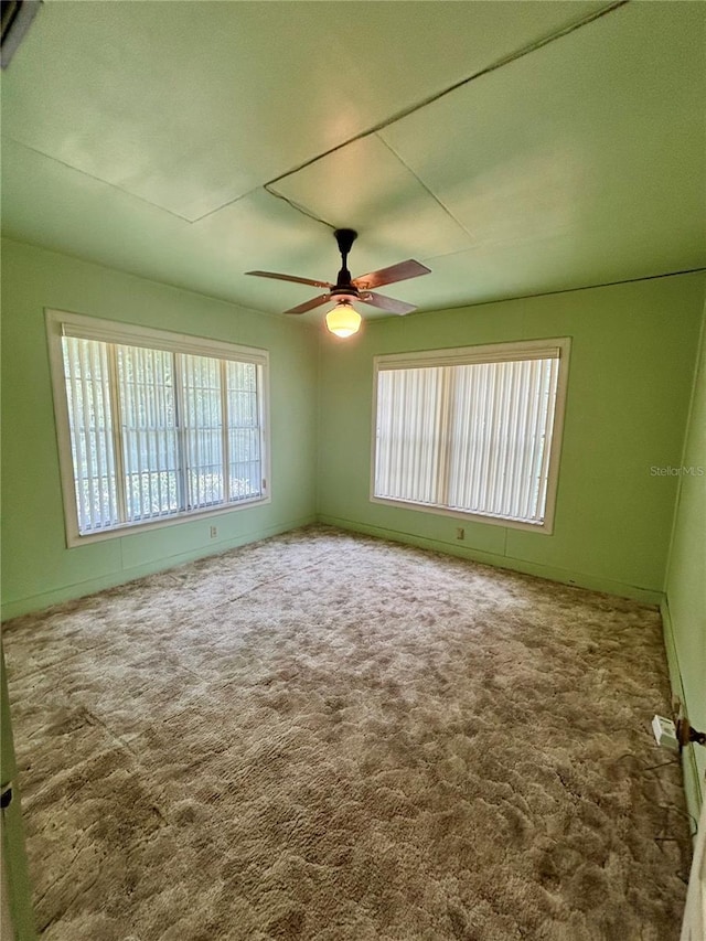 empty room featuring plenty of natural light, a ceiling fan, and carpet